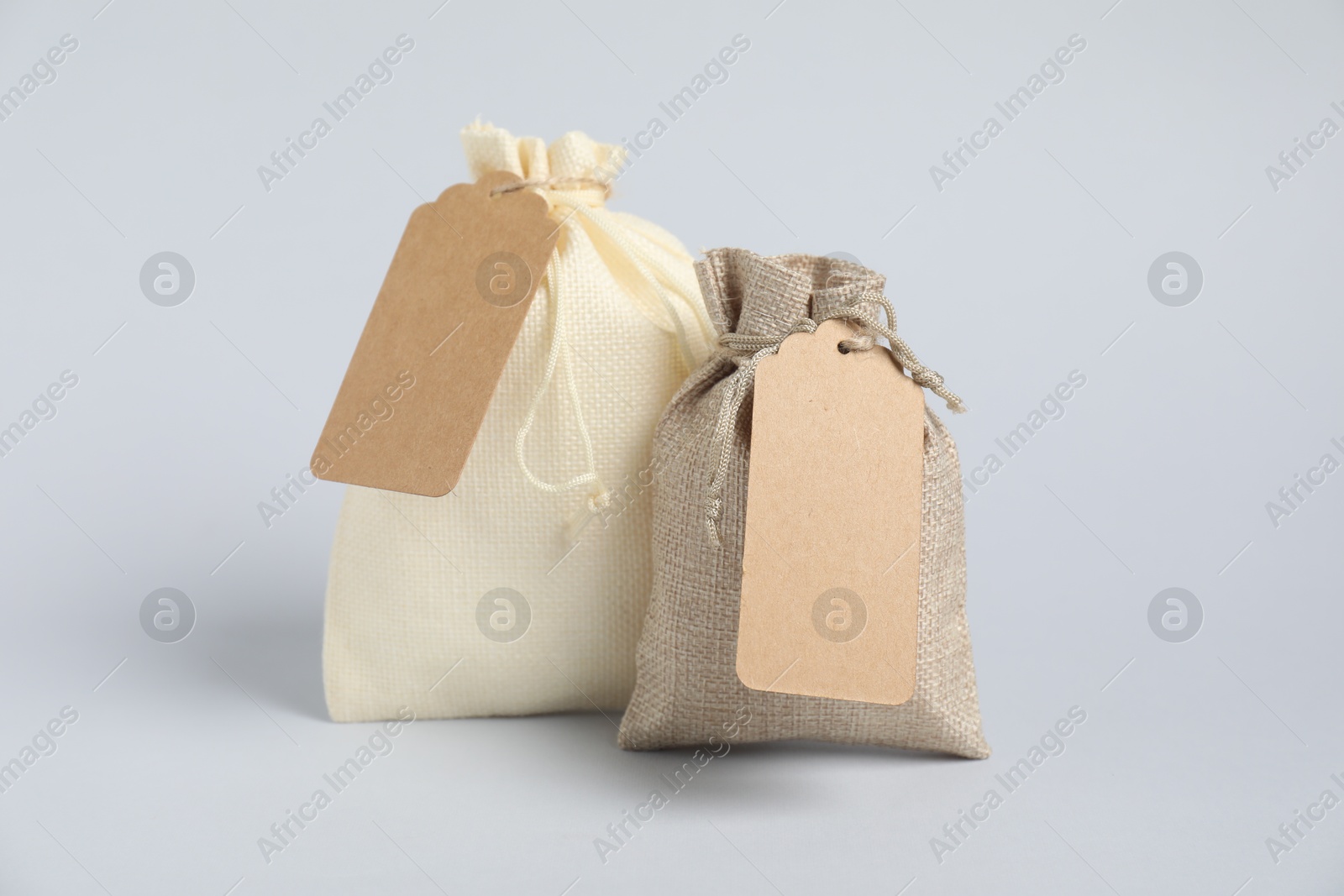 Photo of Burlap bags with tags on light background