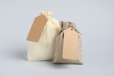 Burlap bags with tags on light background