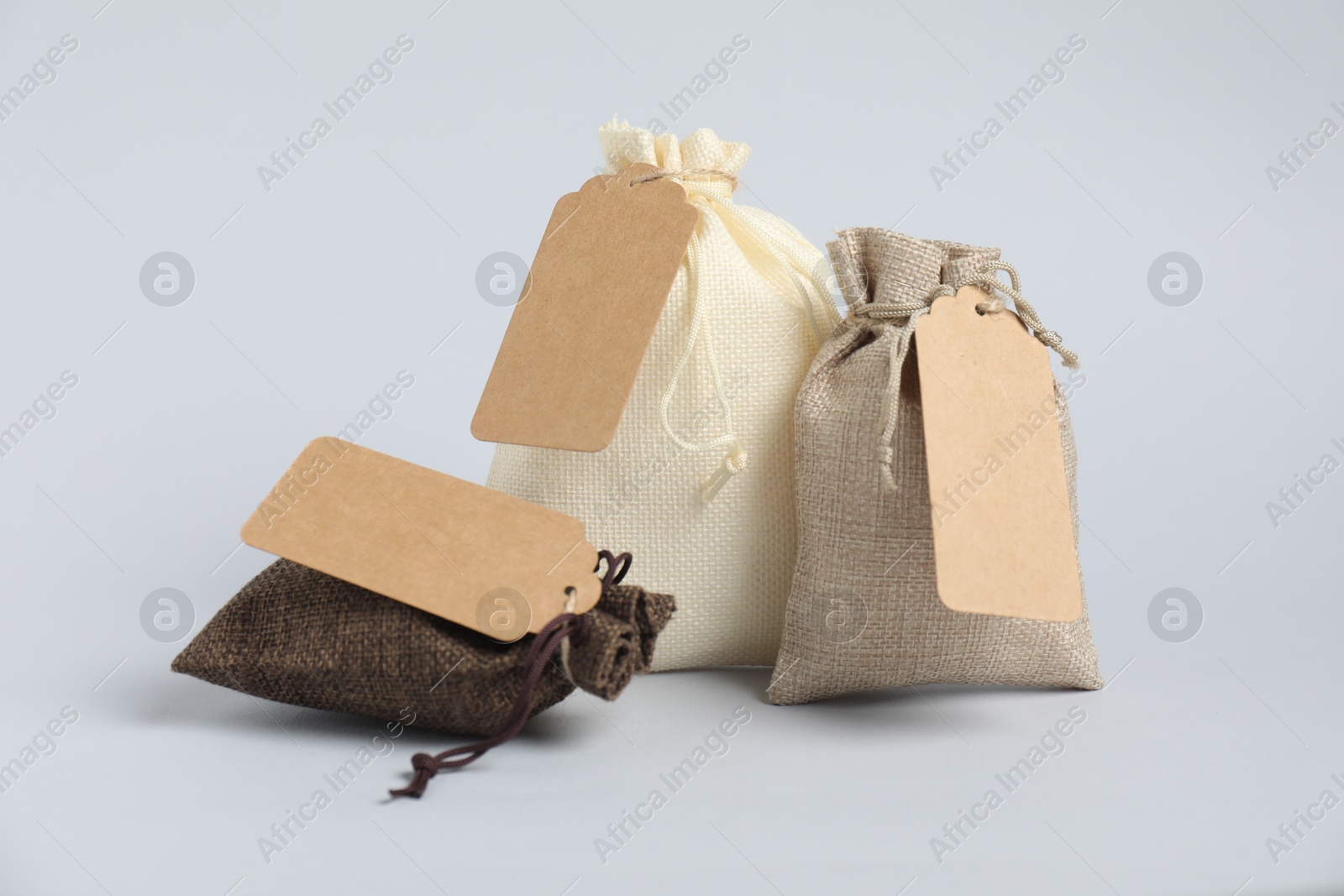 Photo of Burlap bags with tags on light background