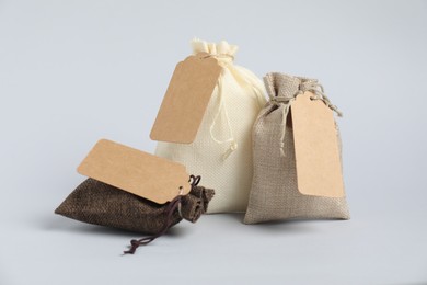 Photo of Burlap bags with tags on light background