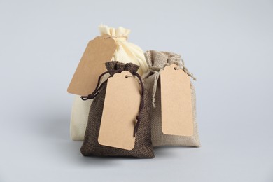 Photo of Burlap bags with tags on light background