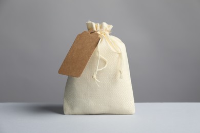 Photo of One burlap bag with tag on light table against grey background