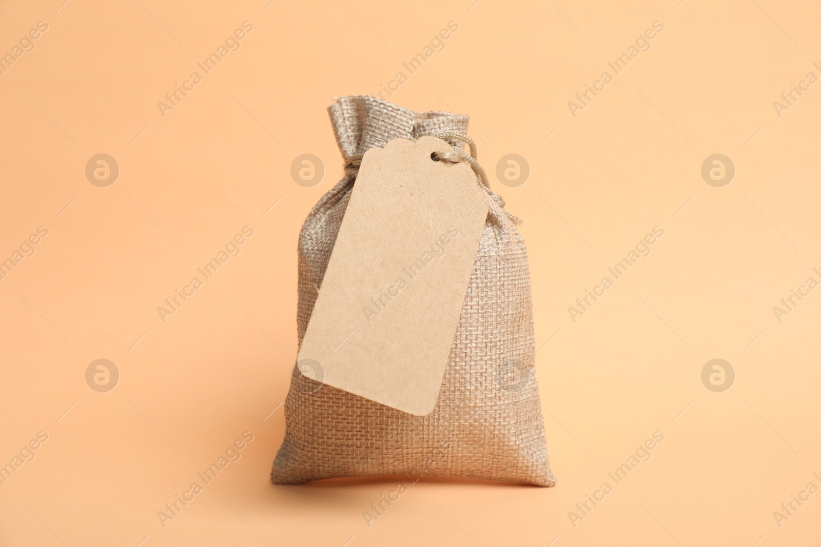 Photo of One burlap bag with tag on beige background