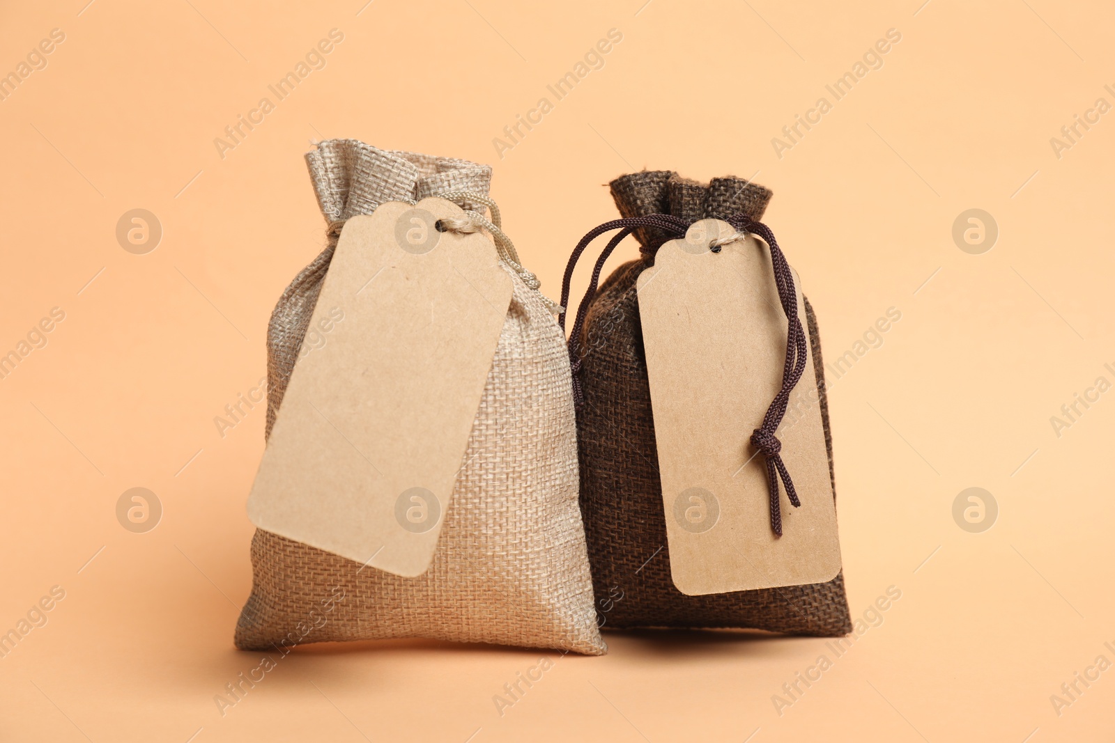 Photo of Burlap bags with tags on beige background