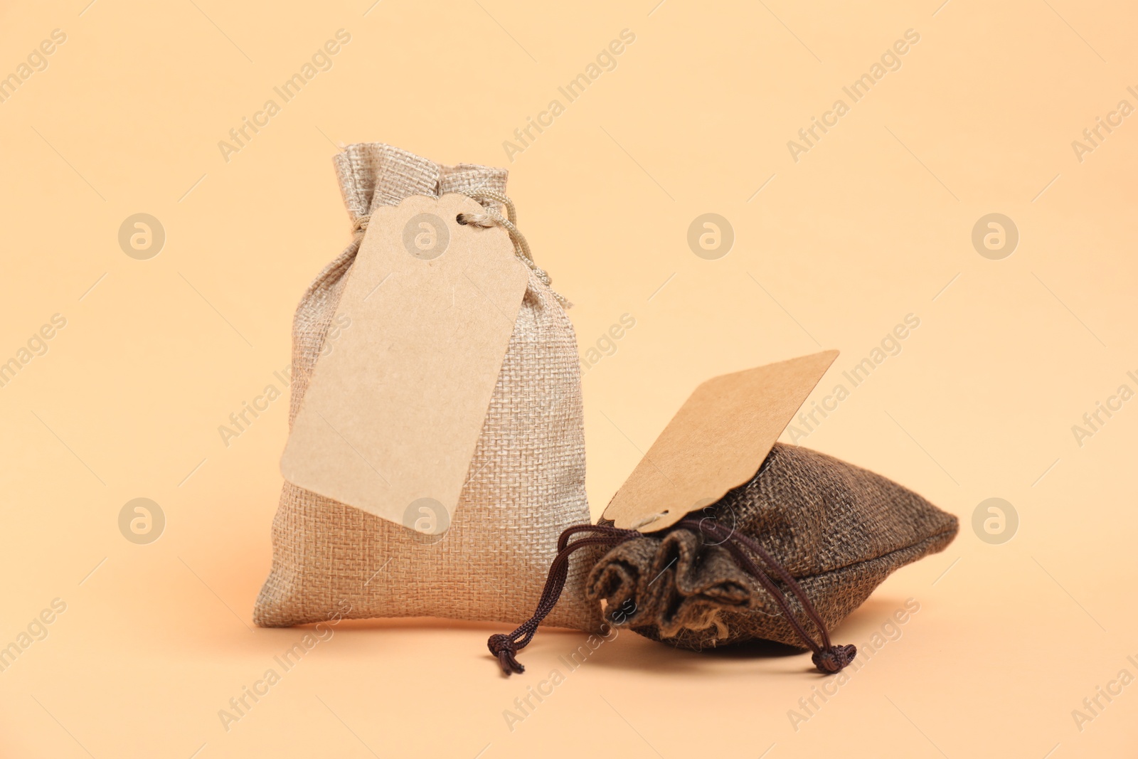 Photo of Burlap bags with tags on beige background