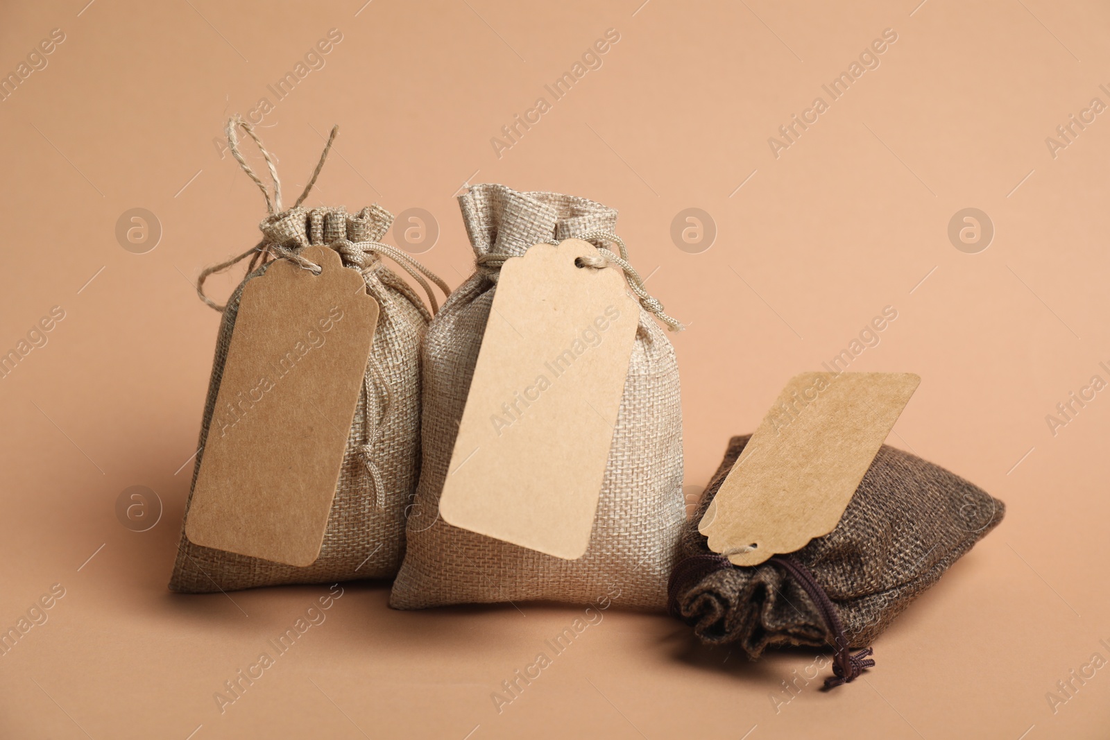 Photo of Burlap bags with tags on beige background