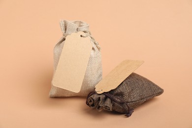 Photo of Burlap bags with tags on beige background