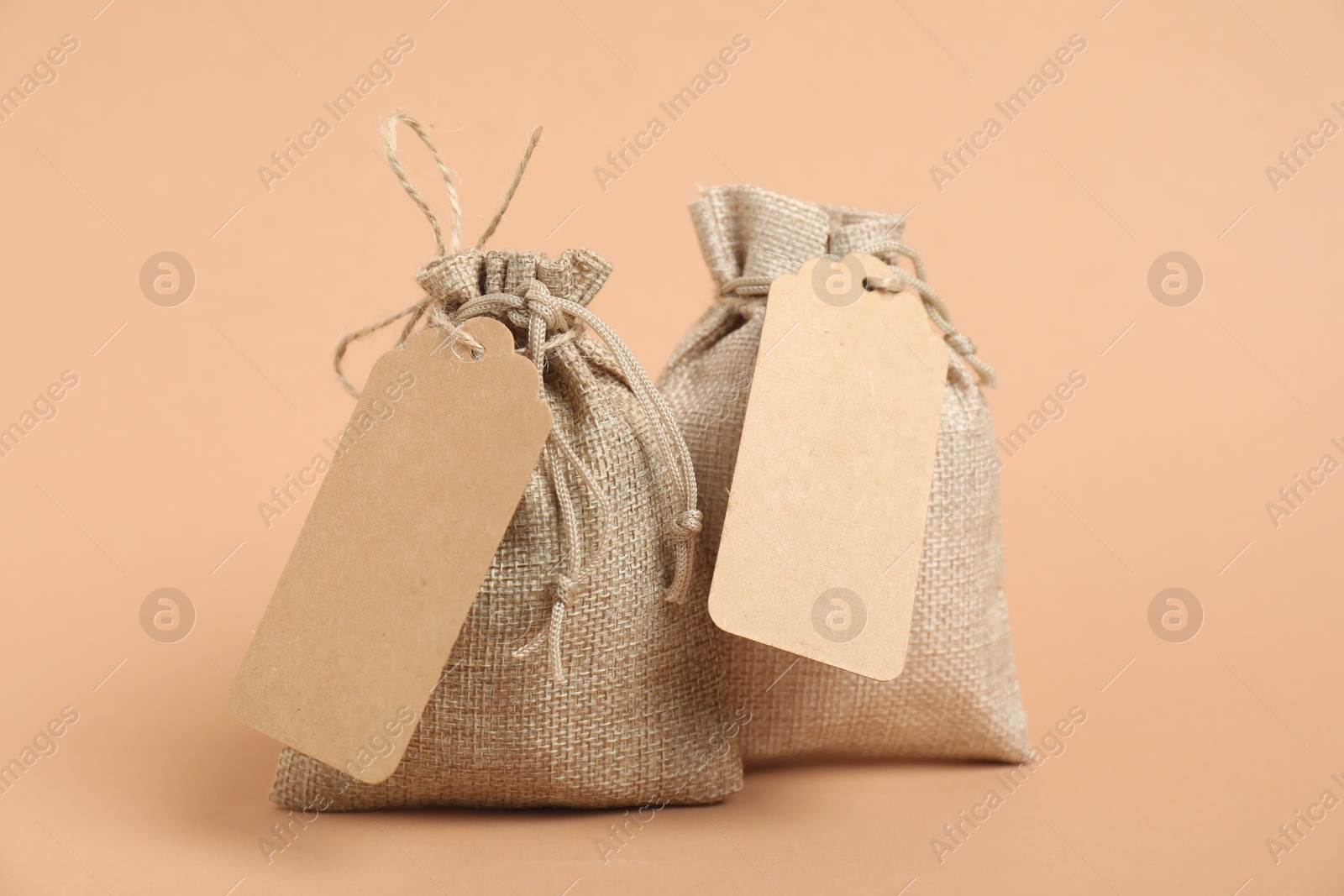 Photo of Burlap bags with tags on beige background