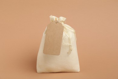 Photo of One burlap bag with tag on beige background