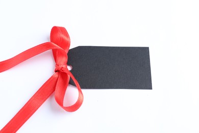 Photo of Blank tag with ribbon bow isolated on white