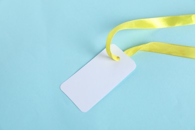 Photo of Blank tag with ribbon on light blue background, top view