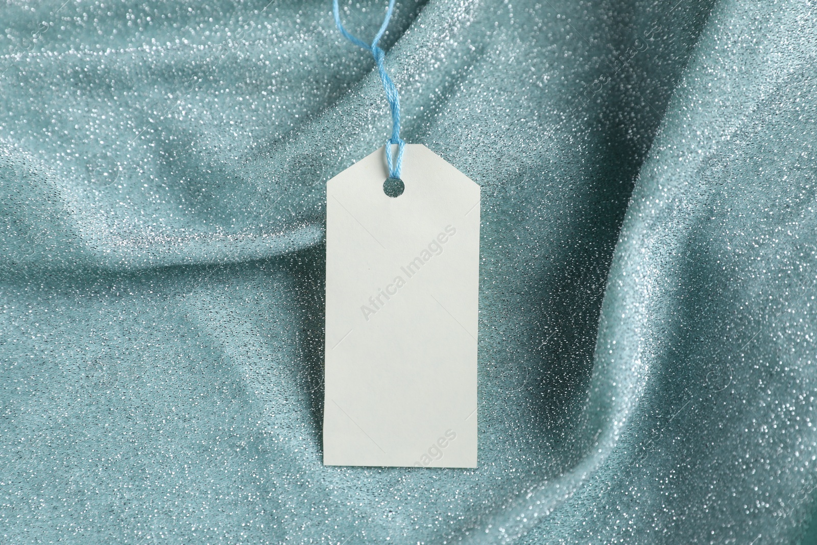 Photo of Blank tag with string on teal fabric, closeup