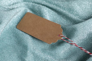 Photo of Blank tag with string on teal fabric, closeup