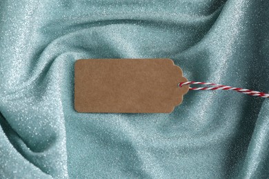 Photo of Blank tag with string on teal fabric, top view