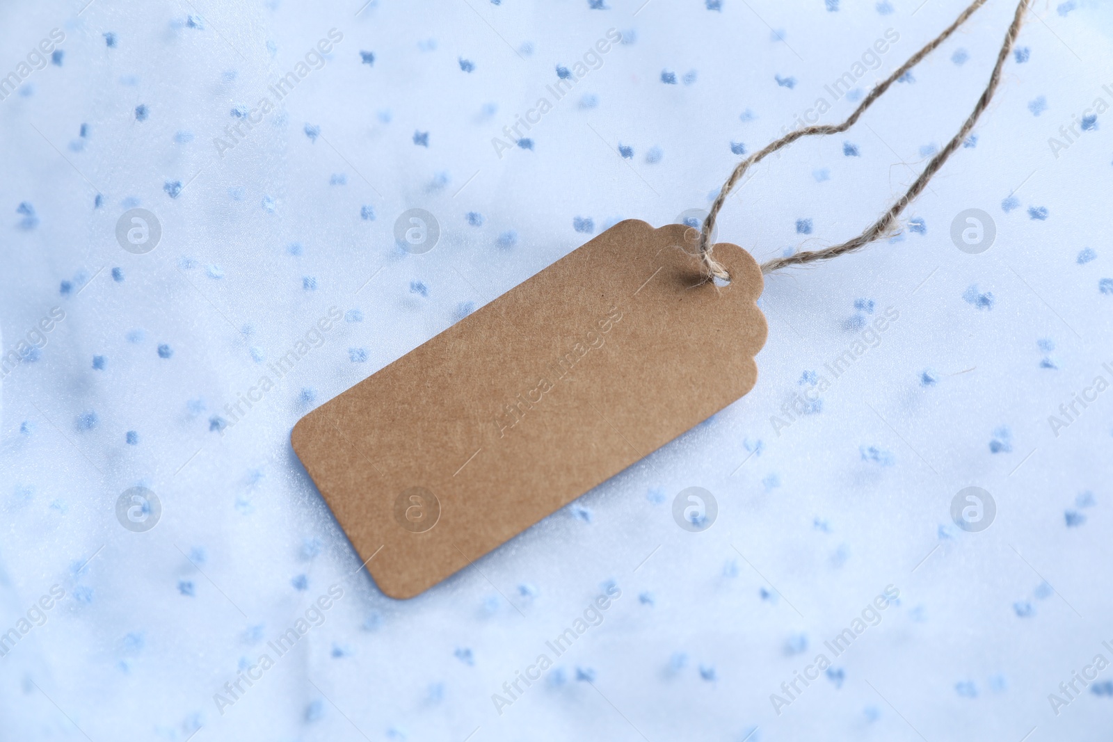 Photo of Blank tag with string on white fabric, closeup