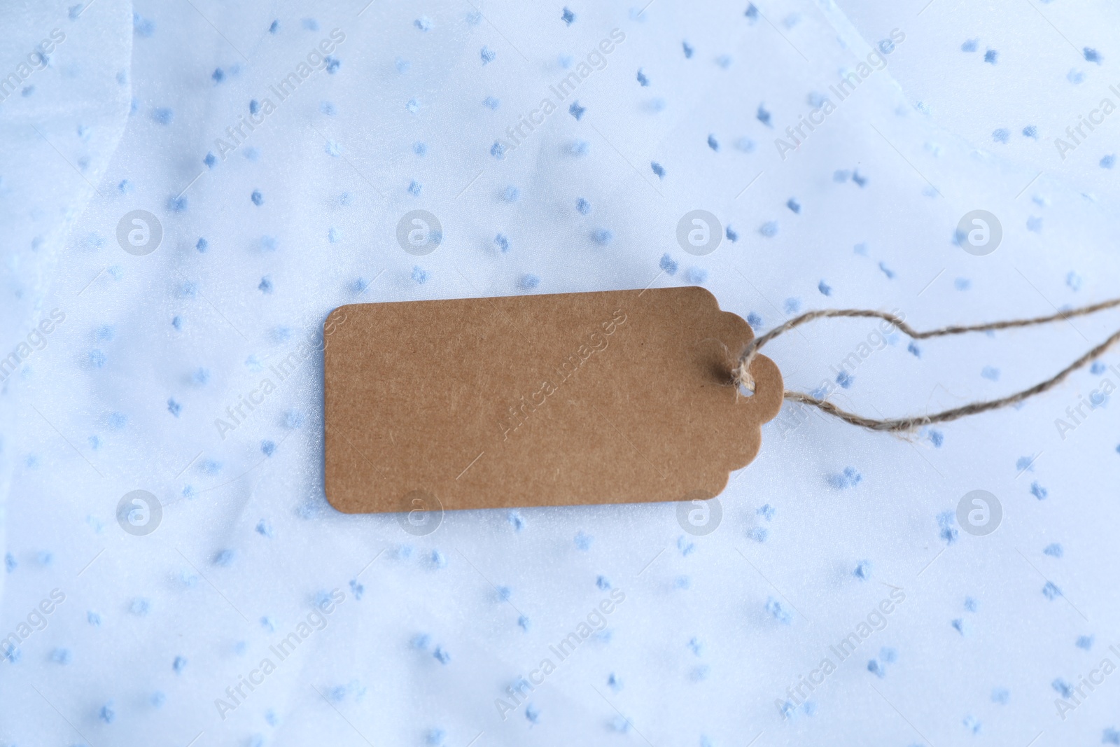 Photo of Blank tag with string on white fabric, closeup