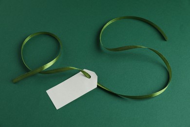 Photo of Blank tag with ribbon on green background