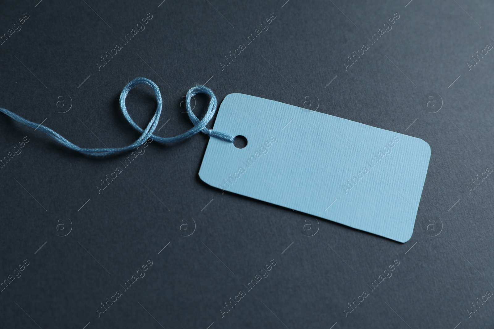 Photo of Blank tag with string on grey background, closeup