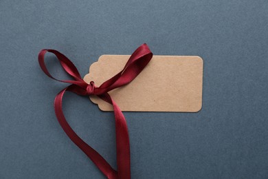 Photo of Blank tag with ribbon bow on grey background, top view