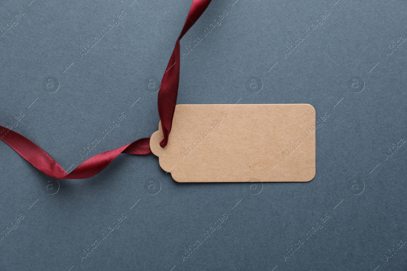 Photo of Blank tag with ribbon on grey background, top view