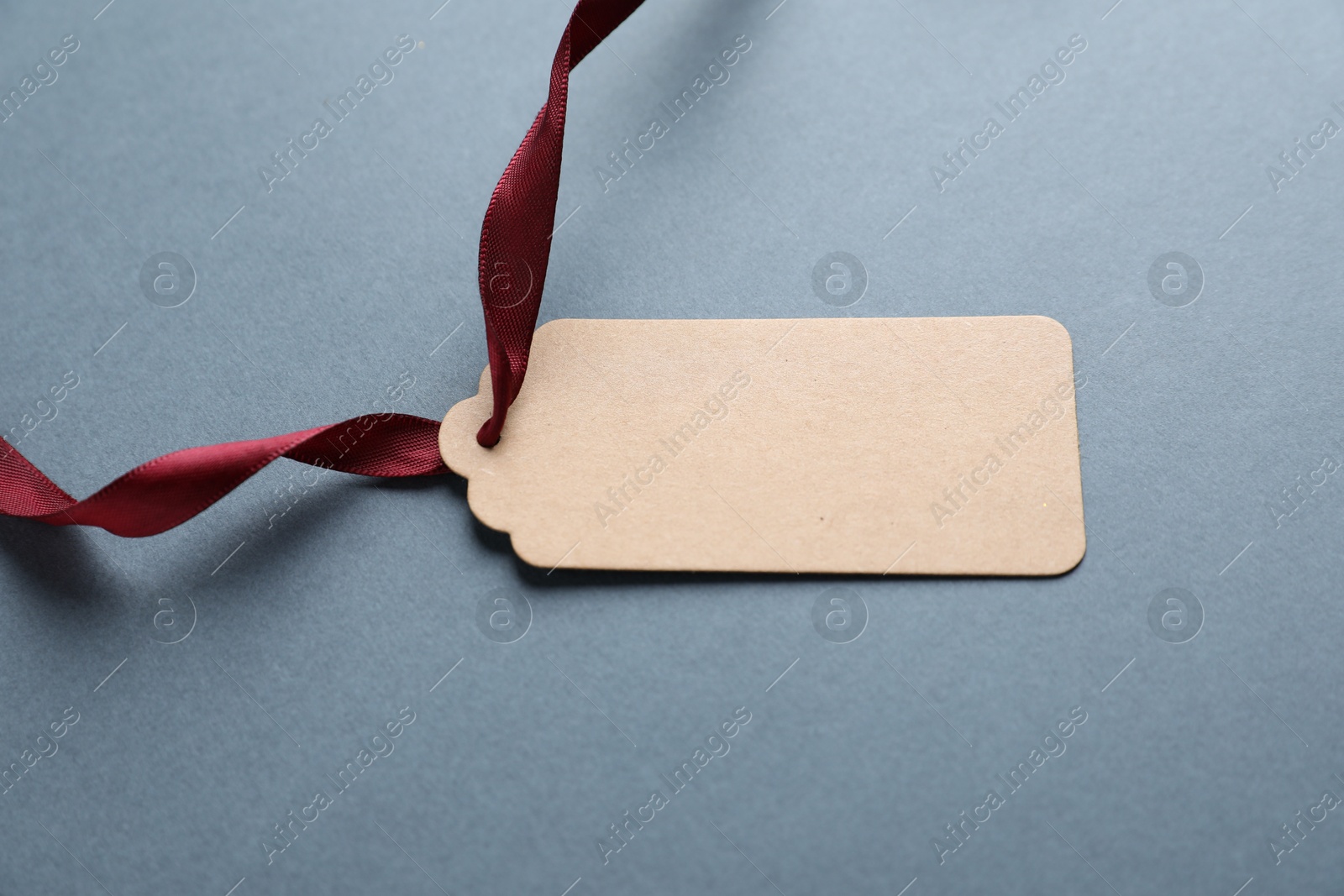 Photo of Blank tag with ribbon on grey background, closeup