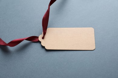 Photo of Blank tag with ribbon on grey background, closeup