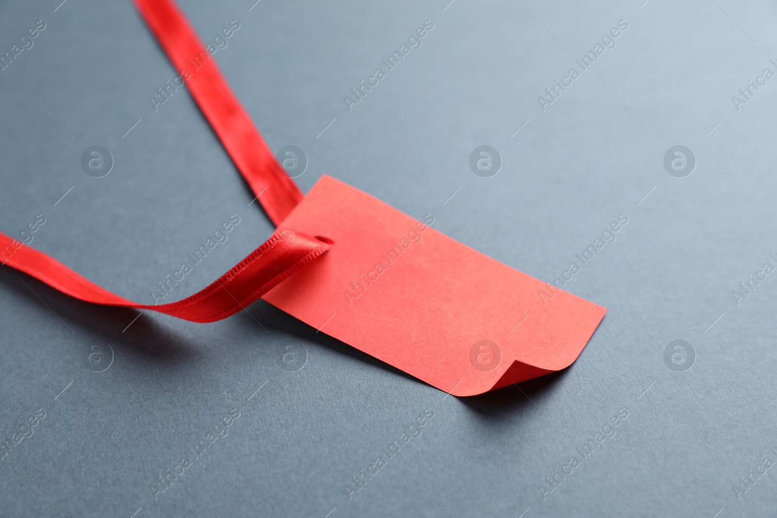 Photo of Blank tag with ribbon on grey background, closeup