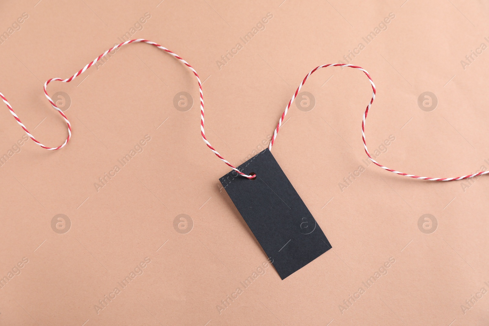 Photo of Blank tag with string on beige background, top view