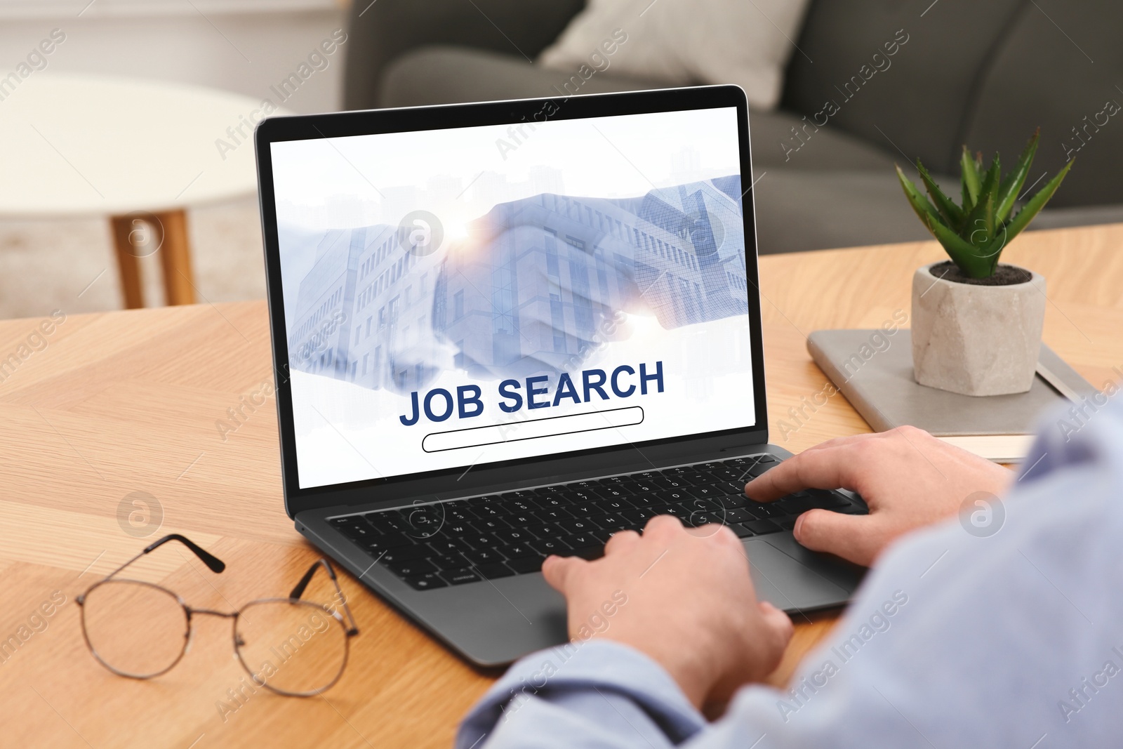 Image of Man looking for job using employment website on laptop at home, closeup