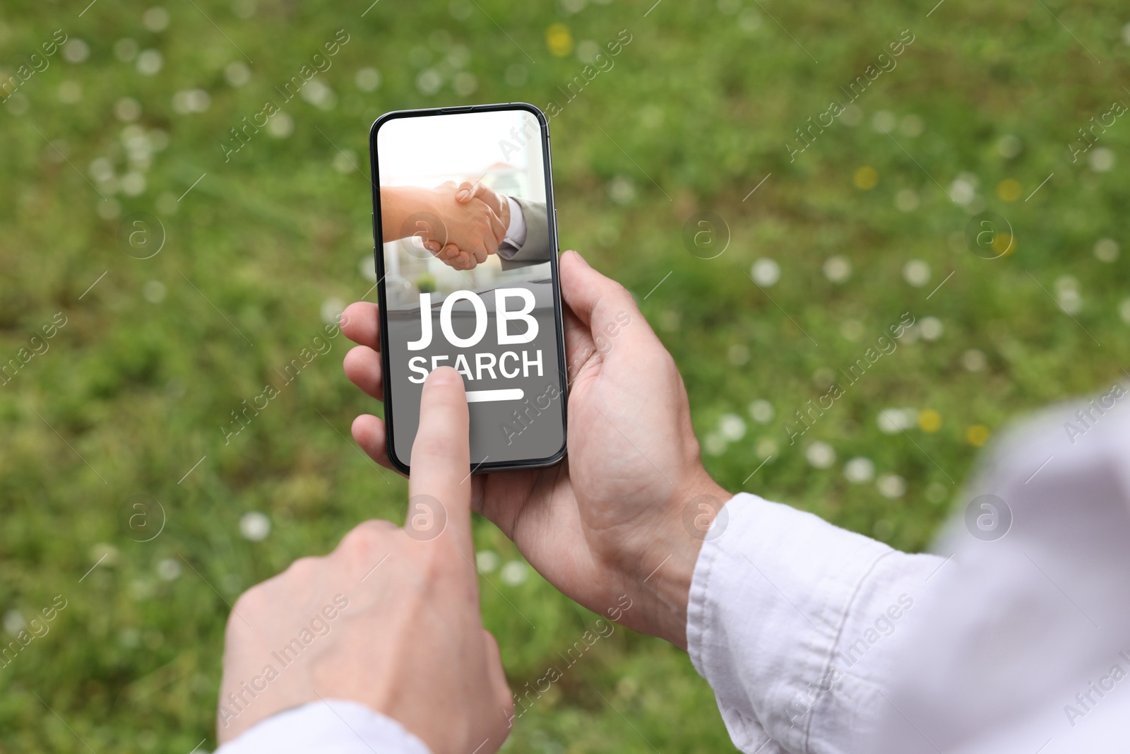 Image of Man looking for job using employment website on mobile phone outdoors, closeup