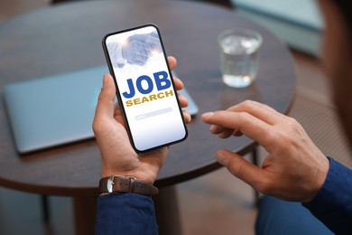 Image of Job search. Man using employment website on mobile phone at cafe, closeup