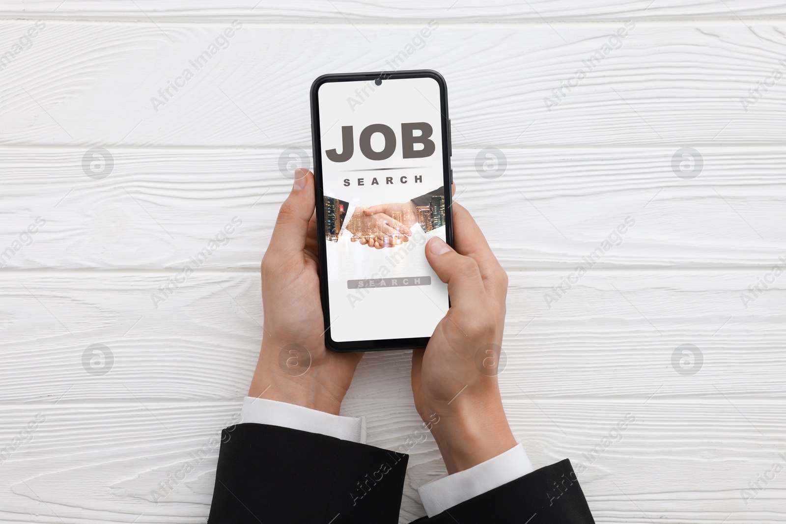 Image of Job search. Woman using employment website on mobile phone at white wooden table, top view