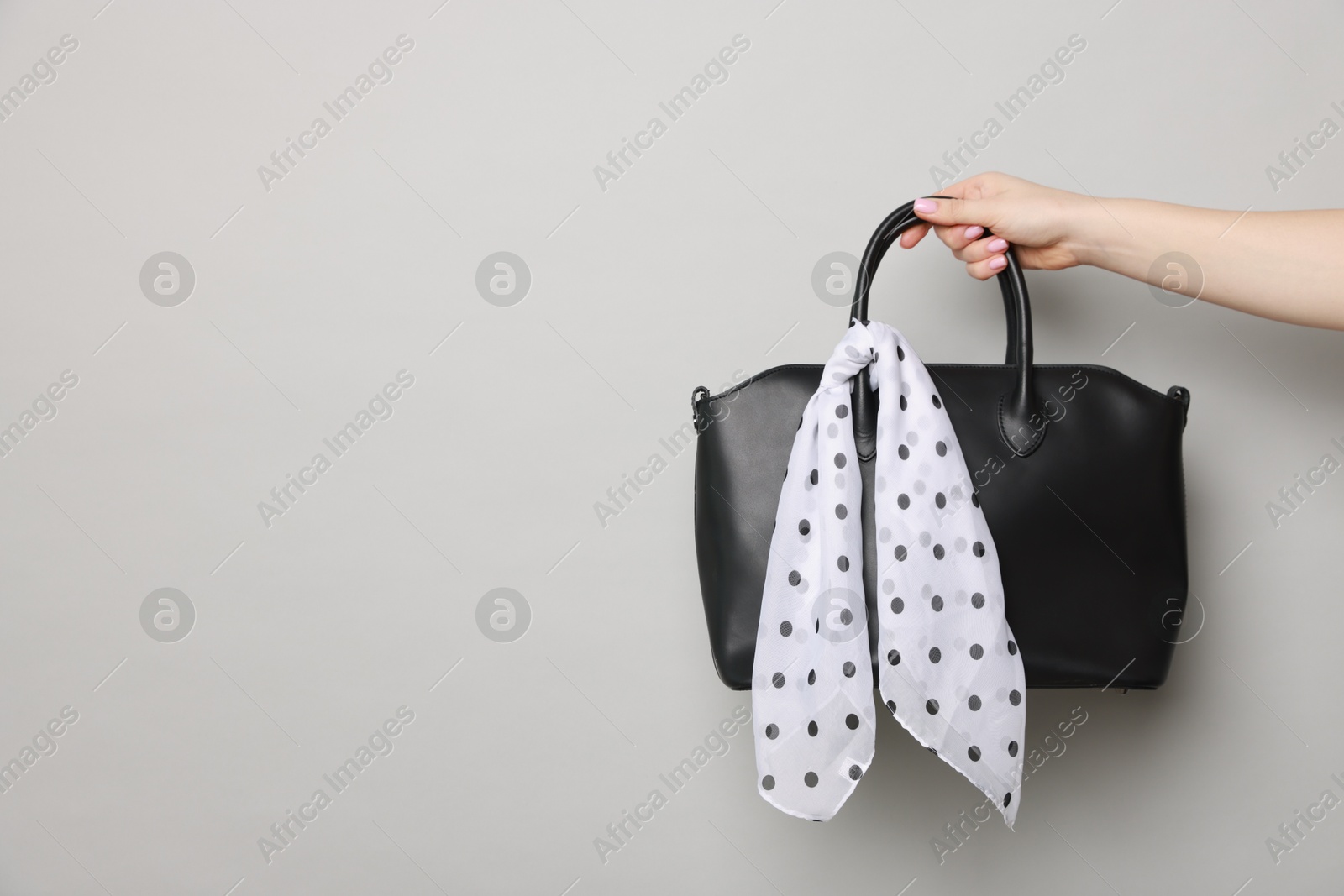 Photo of Woman with beautiful handbag on light grey background, closeup and space for text. Stylish accessory