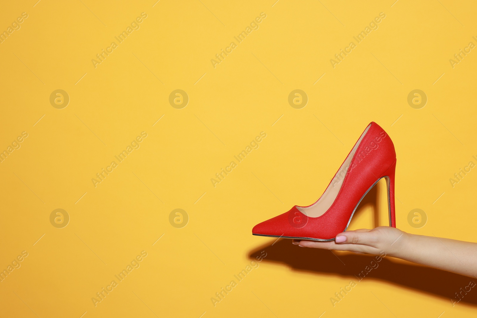 Photo of Woman with beautiful shoe on orange background, closeup. Space for text