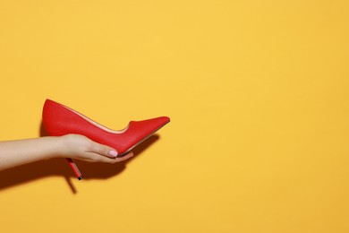 Photo of Woman with beautiful shoe on orange background, closeup. Space for text