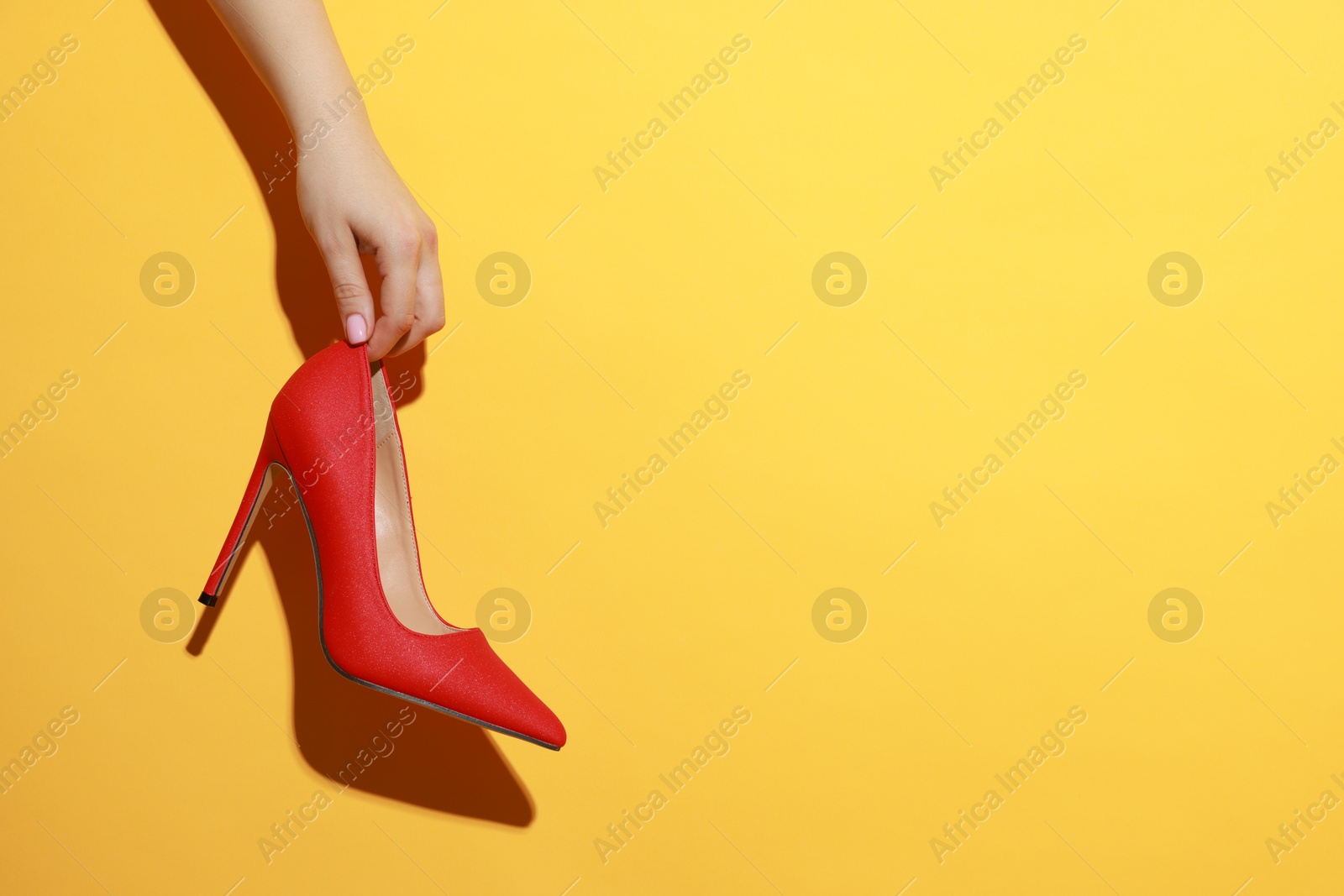 Photo of Woman with beautiful shoe on orange background, closeup. Space for text