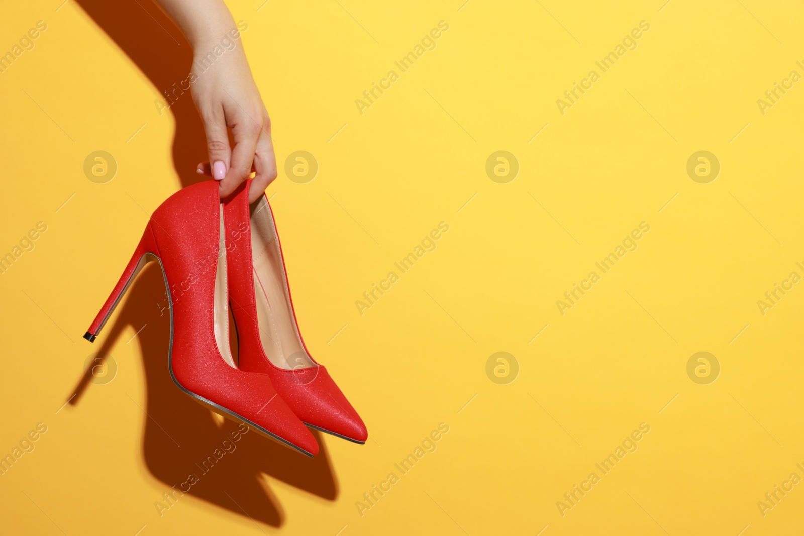 Photo of Woman with beautiful shoes on orange background, closeup. Space for text