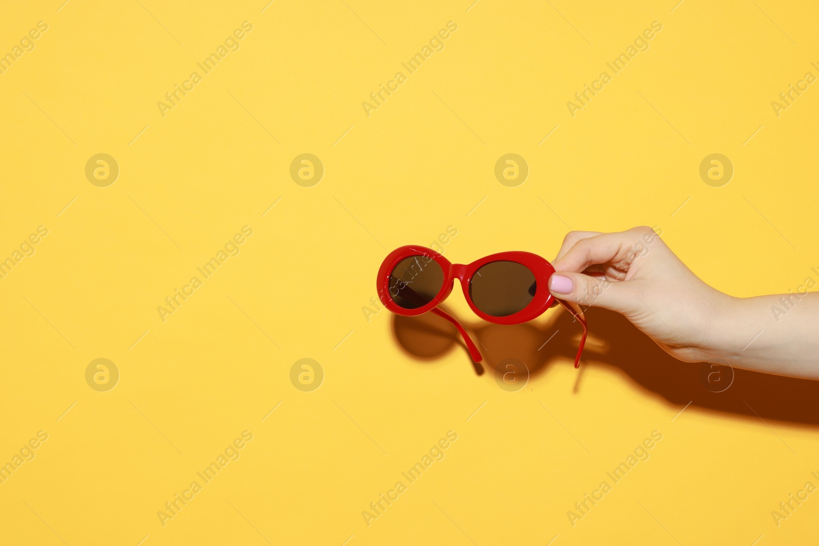 Photo of Woman with beautiful sunglasses on orange background, closeup and space for text. Stylish accessory