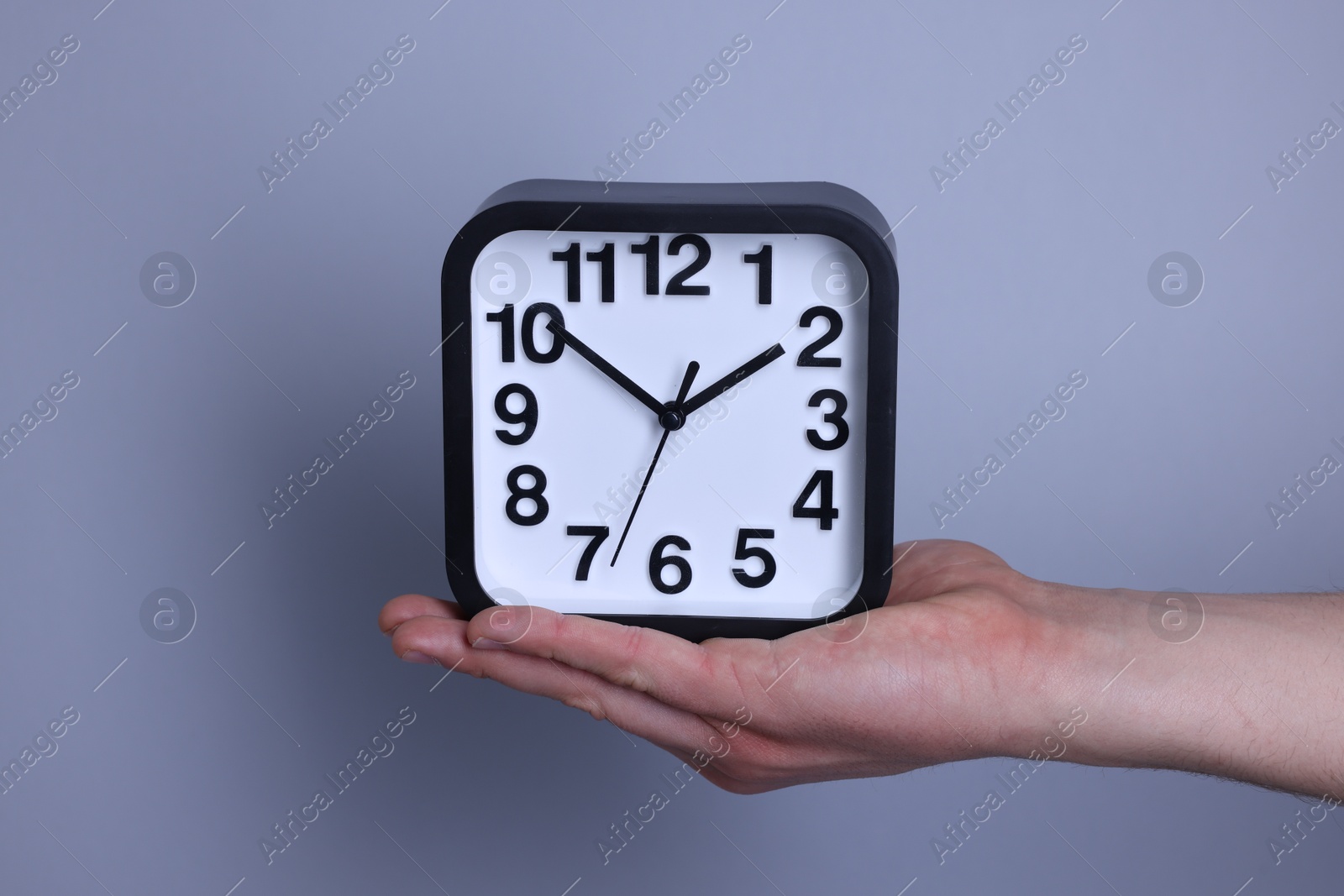 Photo of Man with alarm clock on grey background, closeup