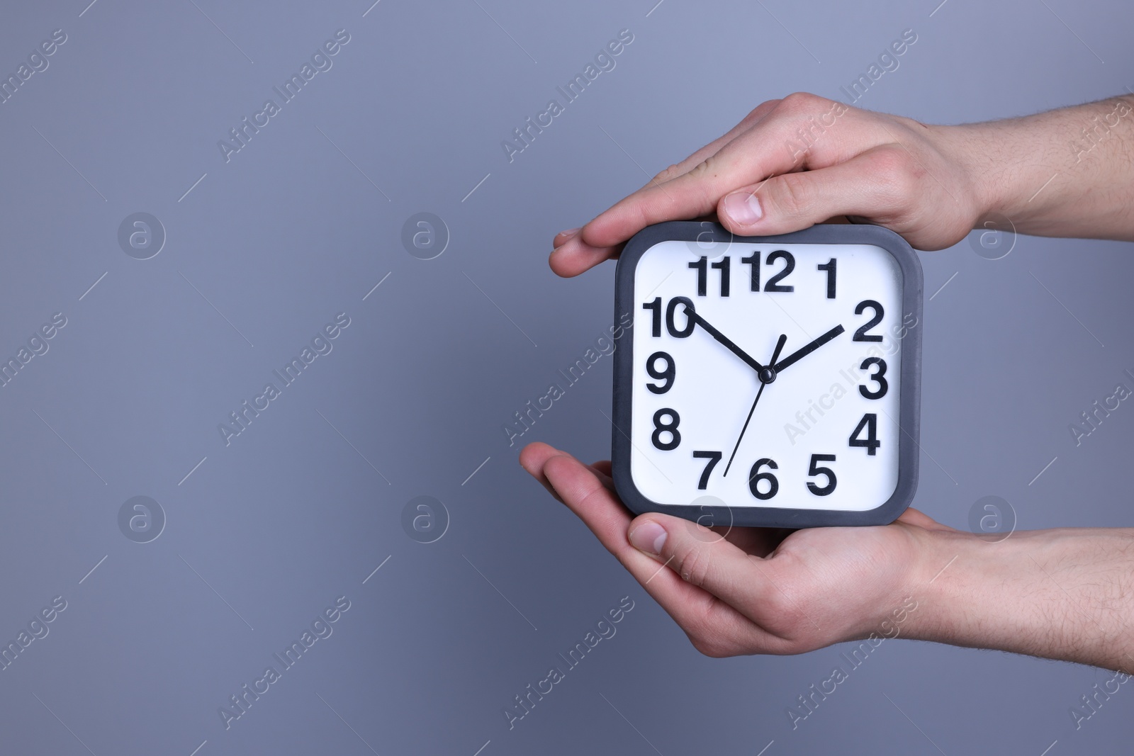 Photo of Man with alarm clock on grey background, closeup. Space for text