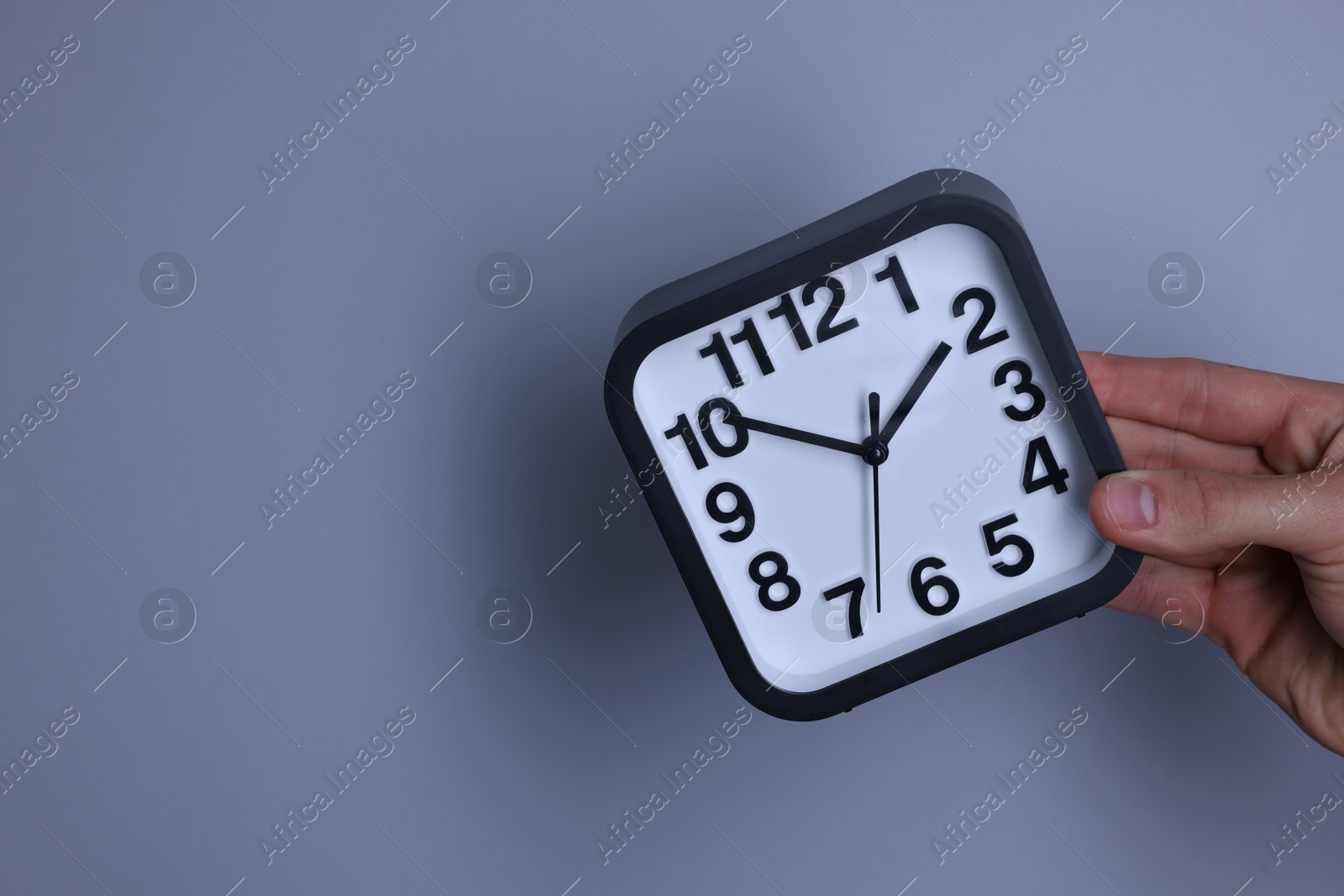 Photo of Man with alarm clock on grey background, closeup. Space for text