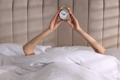 Photo of Woman with alarm clock in bed at home, closeup. Good morning