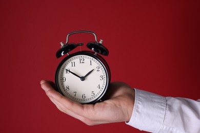 Photo of Man with alarm clock on red background, closeup