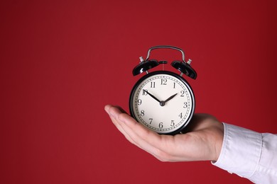 Photo of Man with alarm clock on red background, closeup. Space for text