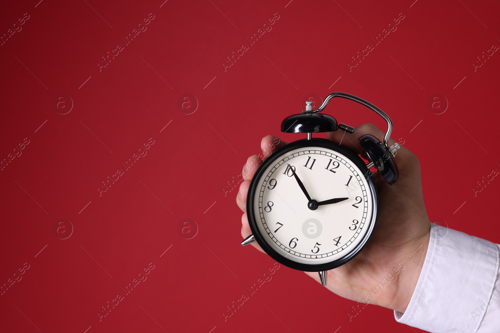 Photo of Man with alarm clock on red background, closeup. Space for text