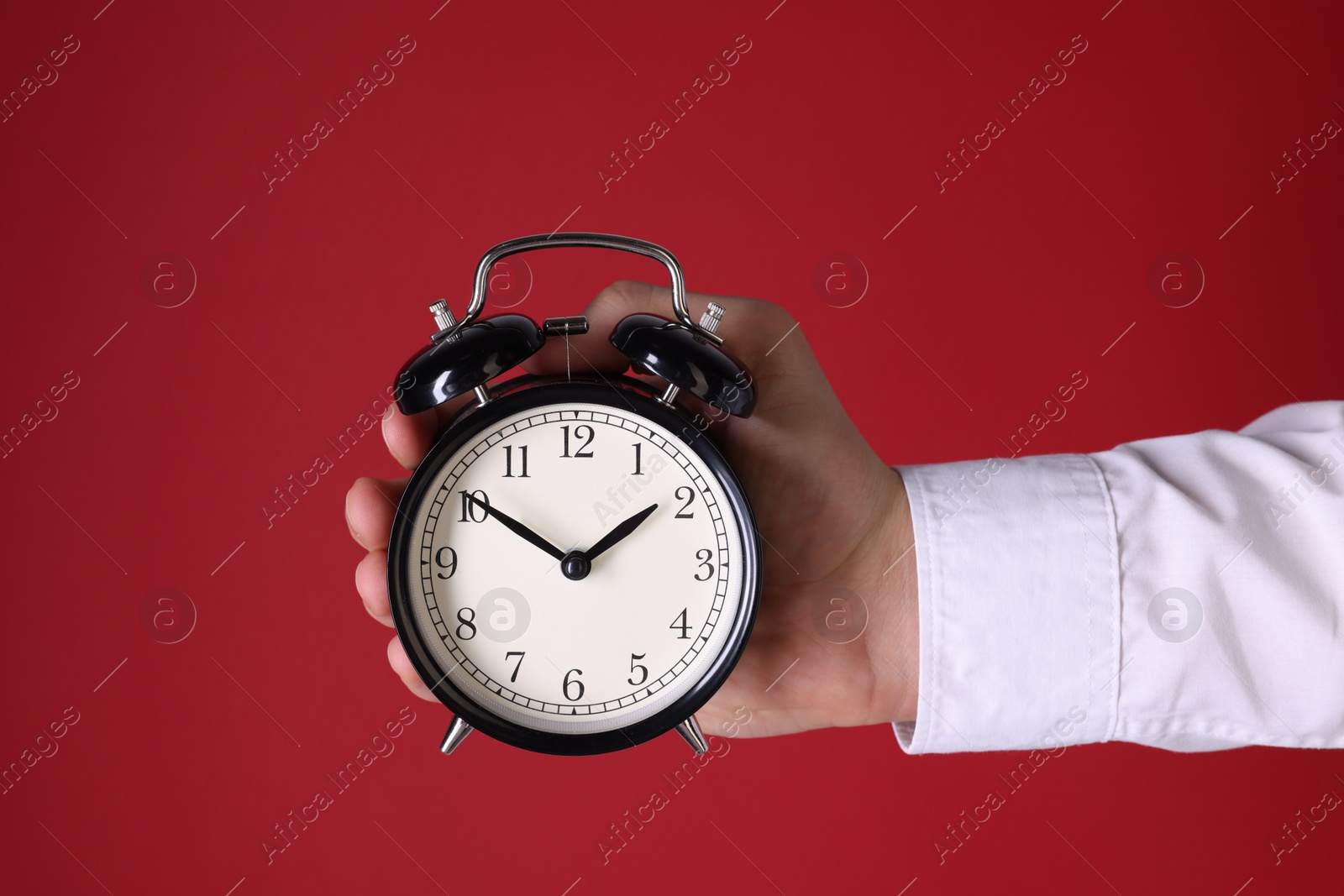 Photo of Man with alarm clock on red background, closeup