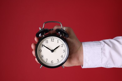 Photo of Man with alarm clock on red background, closeup