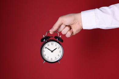 Man with alarm clock on red background, closeup