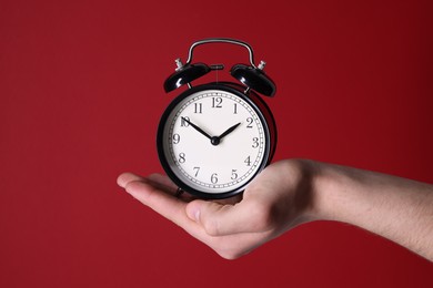 Photo of Man with alarm clock on red background, closeup