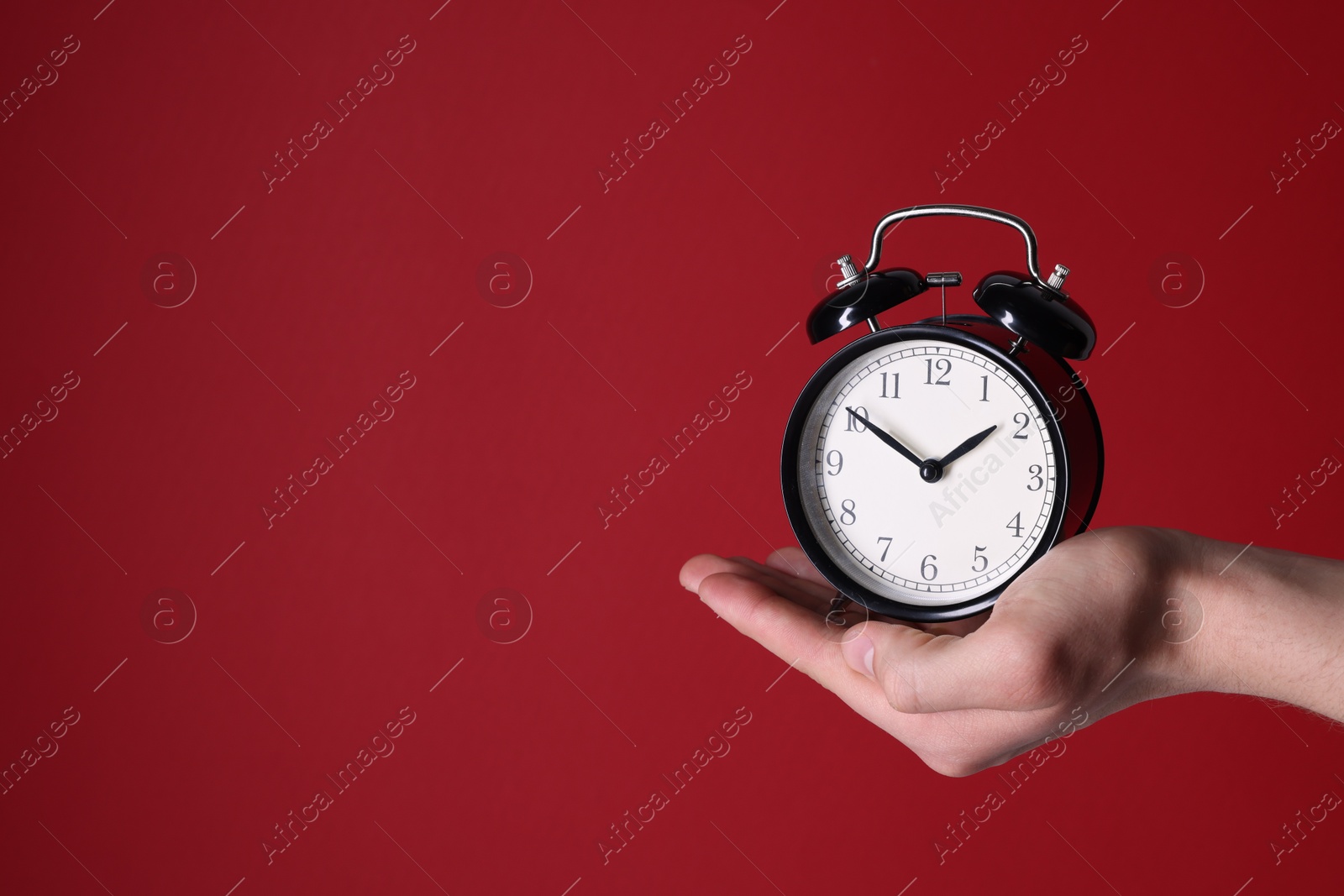 Photo of Man with alarm clock on red background, closeup. Space for text